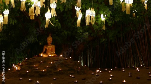 golden buddha image statue with candle light and paper lantern