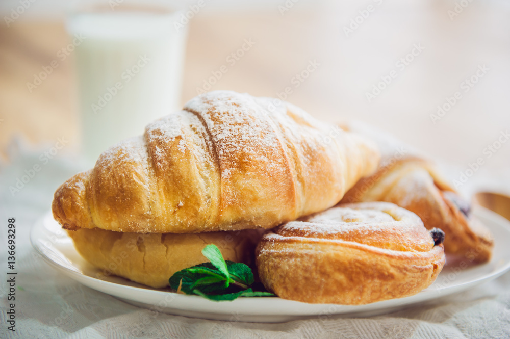 Close up continental breakfast with assortment of fresh pastries and glass of milk on the background. Selective focus