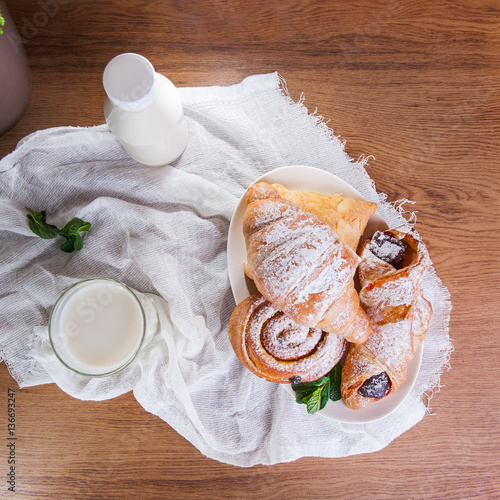 Top view breakfast with assortment of fresh pastries and glass of milk on the white napkin. Selective focus photo