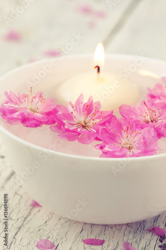 Sakura flowers and candle in a white bowl