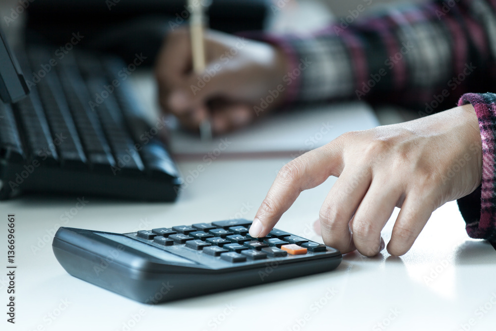 Woman's hands using calculator on table Woman's hands using calculator on table