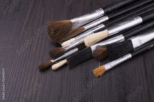 bunch of brushes on dark wooden table