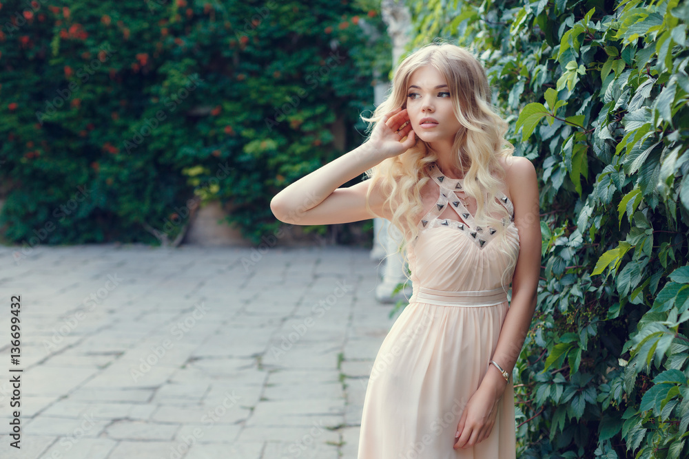 Young beautiful woman in long pink evening dress walking path in park. Fashion style portrait of gorgeous beautiful girl outdoors Young beautiful woman in long pink evening dress walking path in park. Fashion style portrait of gorgeous beautiful girl outdoors