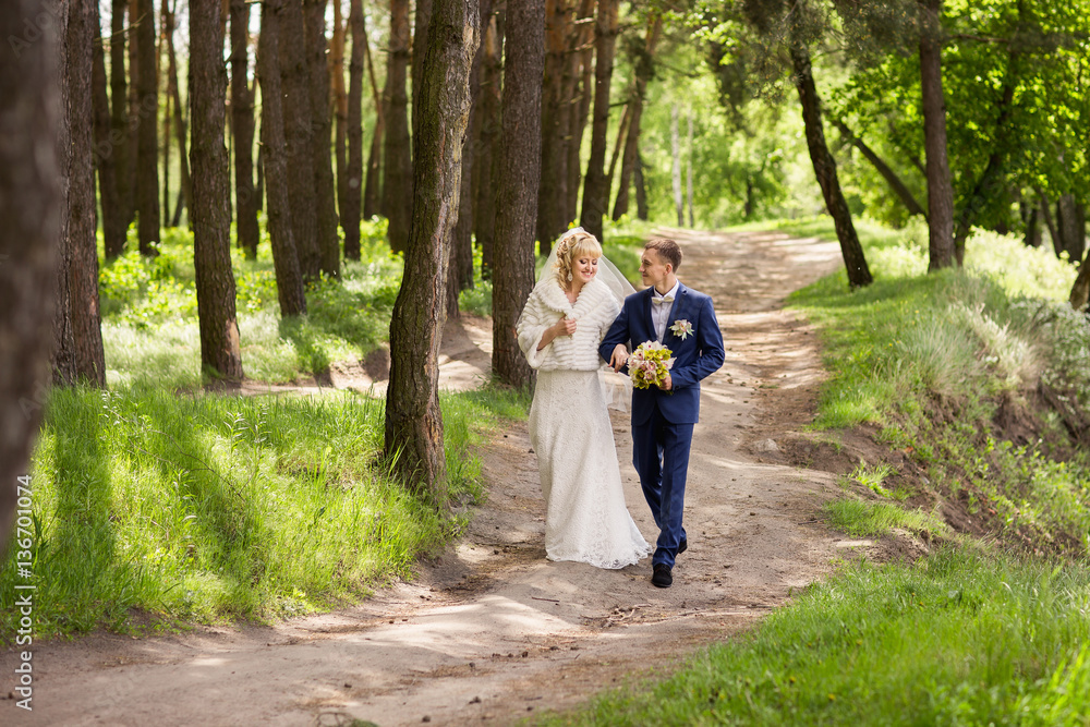 Happy bride and groom walking in forest after their wedding ceremony Happy bride and groom walking in forest after their wedding ceremony