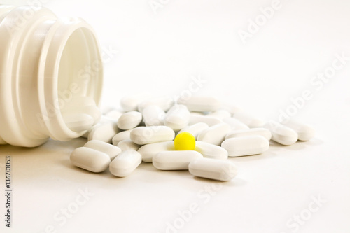 Pills spilling out of pill bottle on white