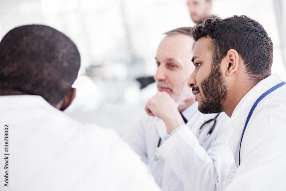 Fototapeta premium Serene bearded physician hearing colleagues during colloquy
