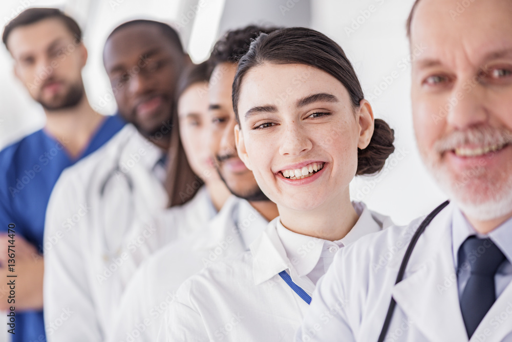 Smiling doctor situating near her colleagues in clinic Smiling doctor situating near her colleagues in clinic