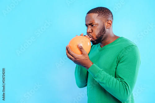 Concentrated guy blowing air into ball