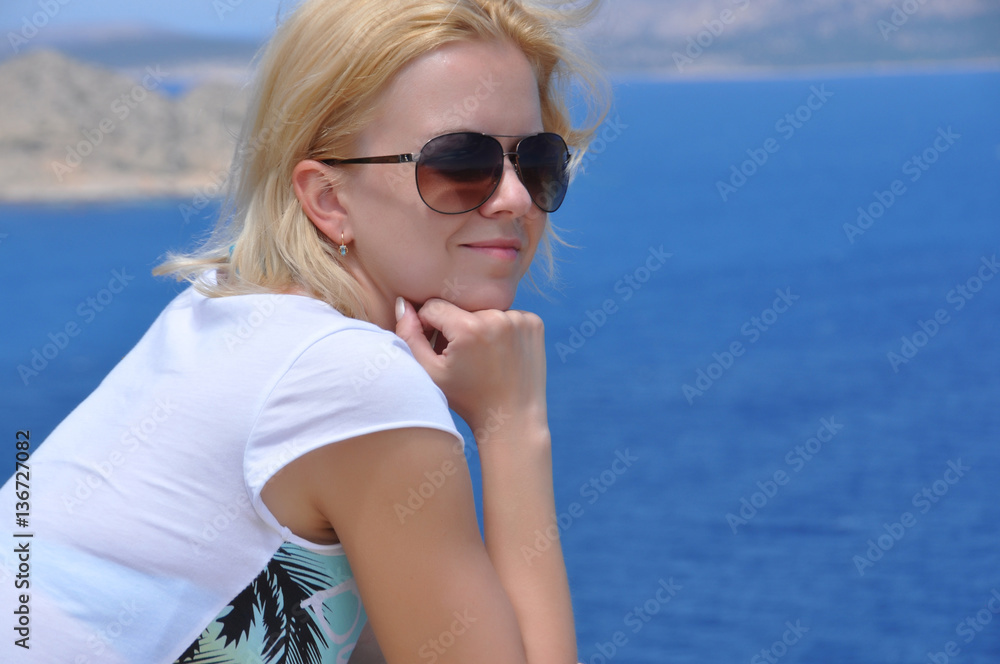 The girl looks at the sea, resting his chin in his hand