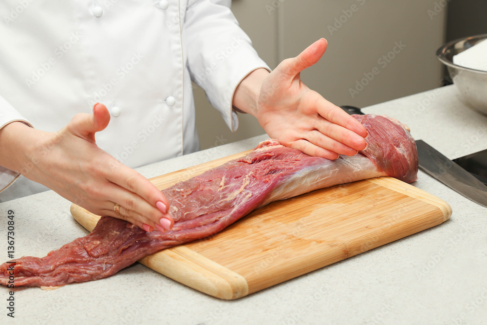 cook cuts a piece of meat