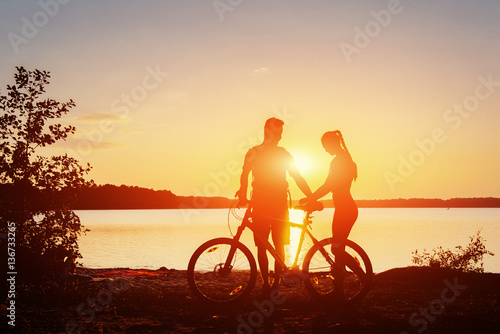 couple on a bicycle at sunset by the lake