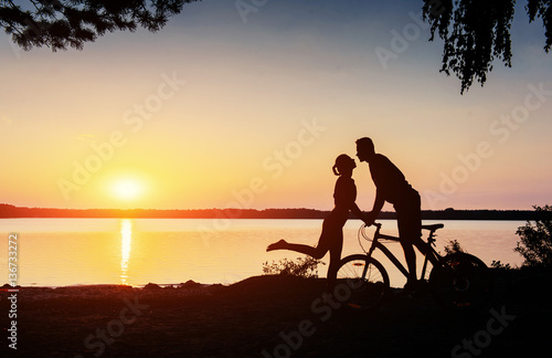 couple on a bicycle at sunset by the lake