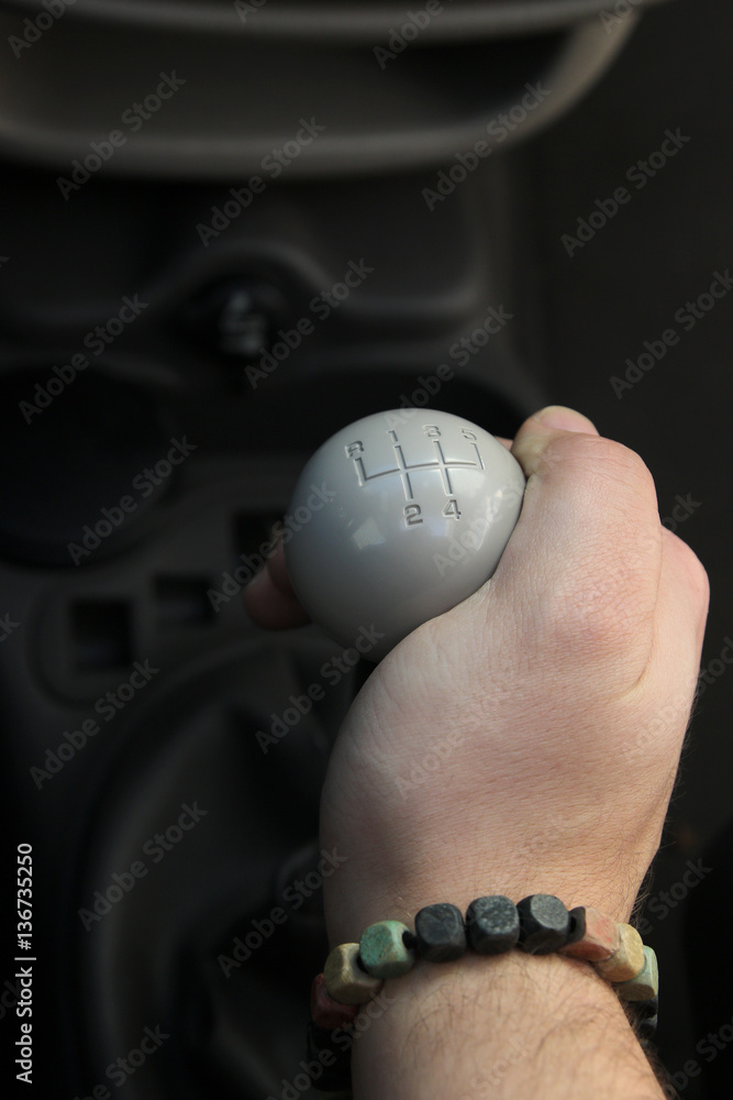 Fototapeta premium Lever manual old school five-speed gearbox and the man's hand that switches transmission. Gear-lever view from above. Handle a manual transmission in a blurry background. five speed manual gear stick