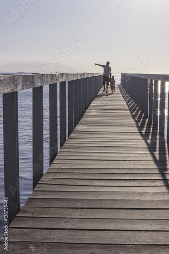 Brazil, State of Rio de Janeiro, Paqueta Island, Man and kid on wooden dock during the sunset photo