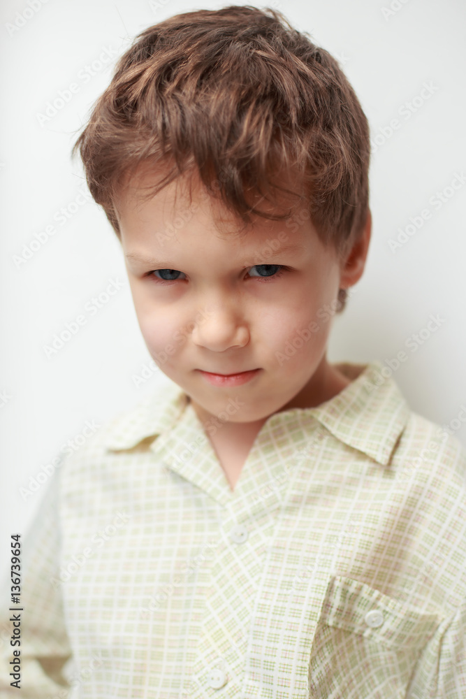 Angry boy junior classes on a white background looks askance offended Angry boy junior classes on a white background looks askance offended