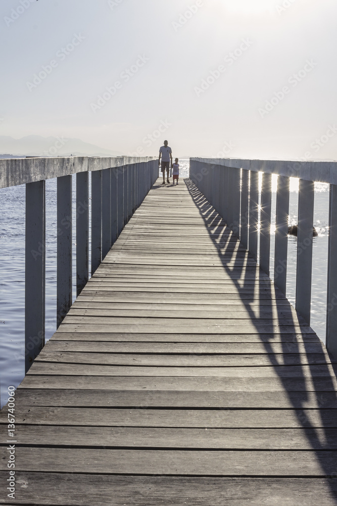 Brazil, State of Rio de Janeiro, Paqueta Island, Man and kid on wooden dock during the sunset