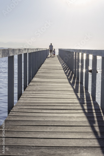 Brazil, State of Rio de Janeiro, Paqueta Island, Man and kid on wooden dock during the sunset photo