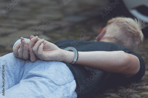 Teenage boy with his hands cuffed behind his back photo