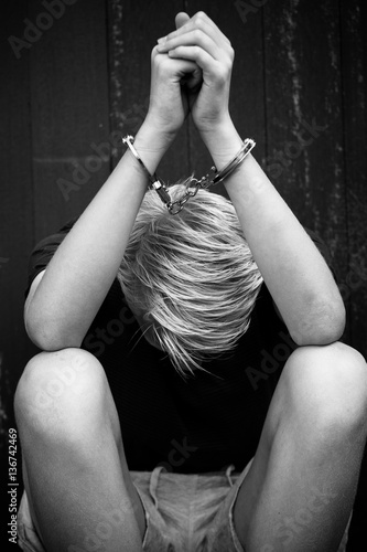 Obraz na plátně Ashamed teenage boy in handcuffs