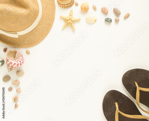 Summer background. Seashells, starfish, sea pebbles, flip flops and straw hat on white background. Flat lay, top view