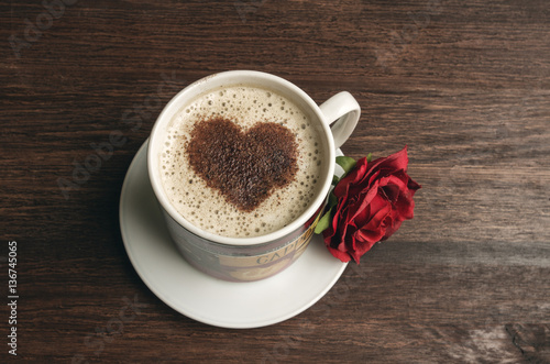 Coffee cup with heart shape and red rose on dark background