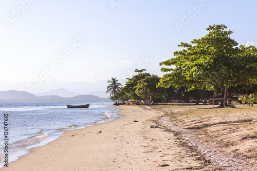 Fototapeta Naklejka Na Ścianę i Meble -  Brazil, State of Rio de Janeiro, Paqueta Island, View of boat by the beach during afternoon with mountains on the background