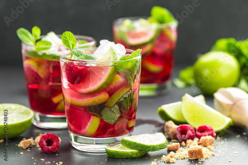 Raspberry mojito cocktail with lime, mint and ice, cold refreshing drink