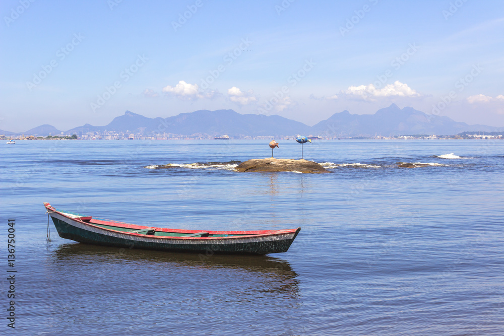 Brazil, State of Rio de Janeiro, Paqueta Island, View of boat and fish sculpture on the bay with the Rio de Janeiro city skyline on the background