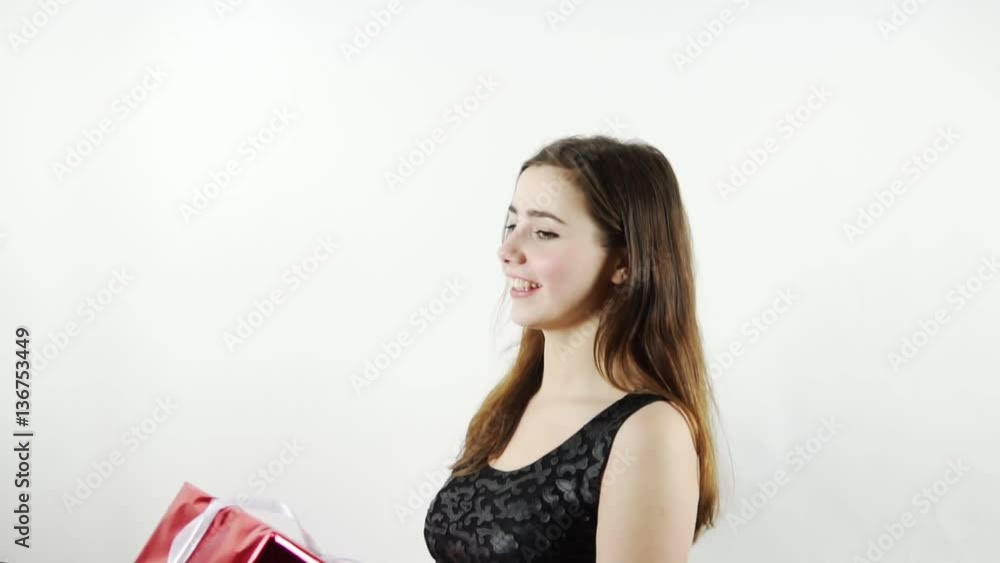 Pretty cheerful girl throw up a decorated red box, slow motion shot. Young woman in black shirt have fun at isoated white background, childlike enjoy her birthday gift. Merry and sincere emotions mood Pretty cheerful girl throw up a decorated red box, slow motion shot. Young woman in black shirt have fun at isoated white background, childlike enjoy her birthday gift. Merry and sincere emotions mood