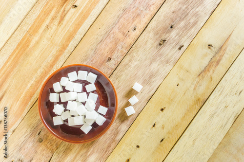 White sugar cubes In brown plate placed on wood