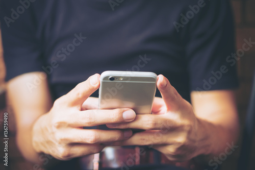 A man using smart phone in modern cafe