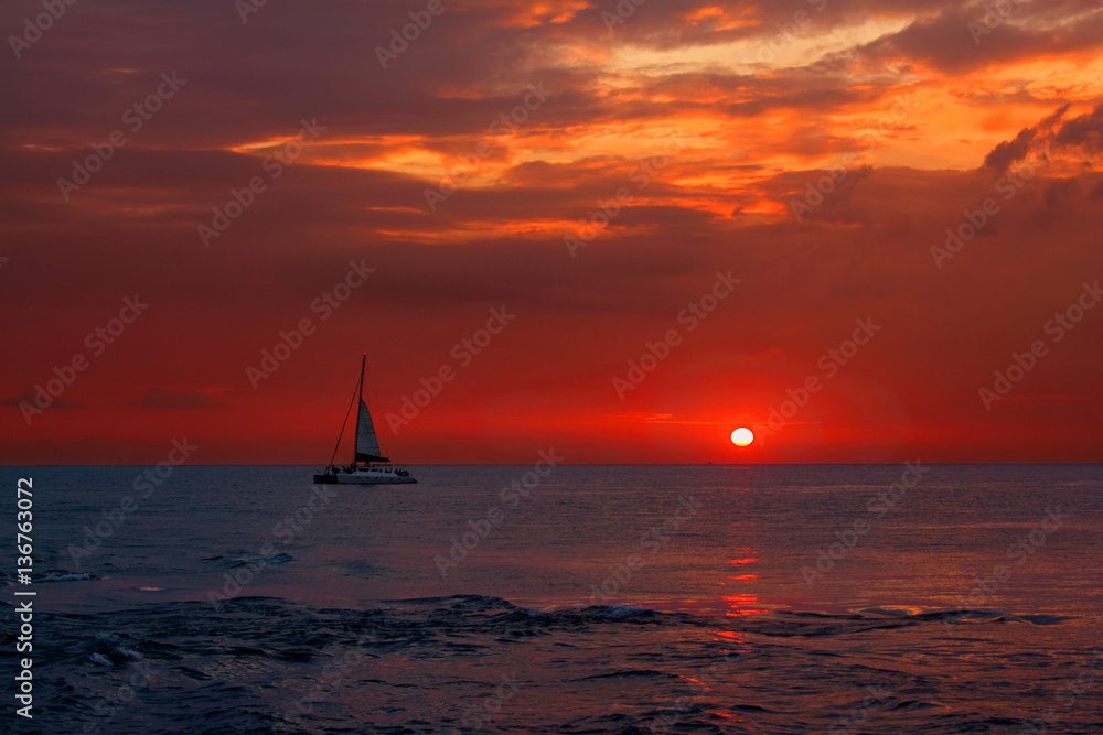 Yacht catamaran in the tropical sea at sunset. Colorful orange sunset sky
