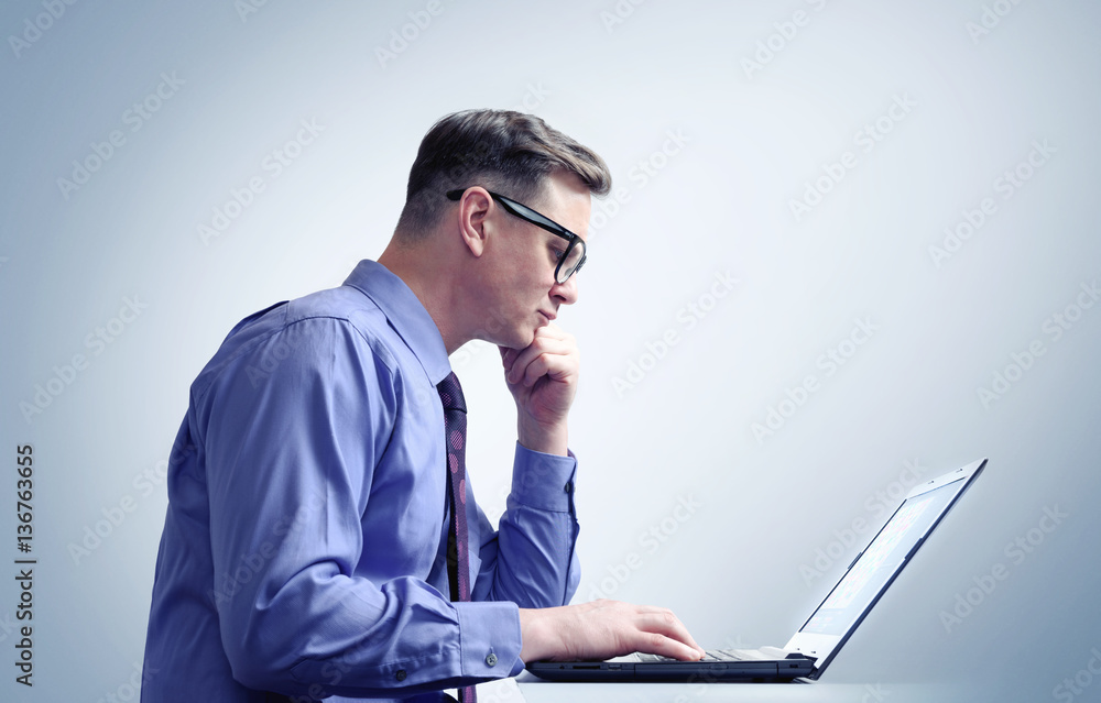 Man with glasses thinking in front of a laptop Man with glasses thinking in front of a laptop