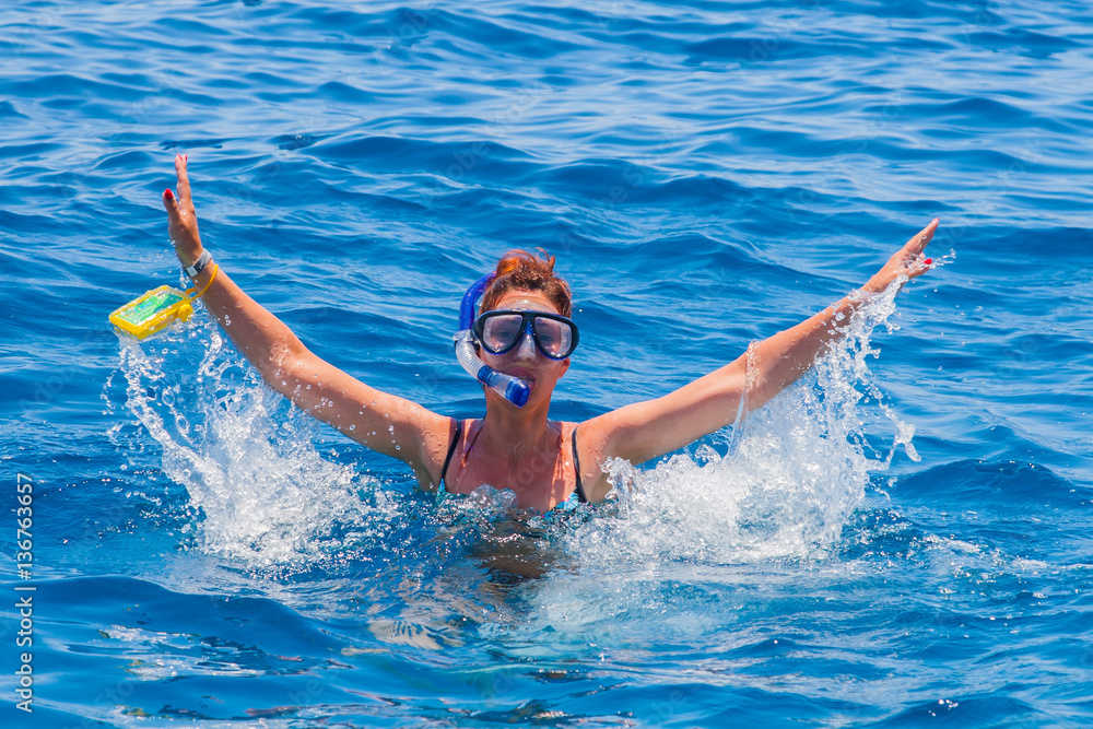 happy woman wearing a mask in the sea, along with a camera