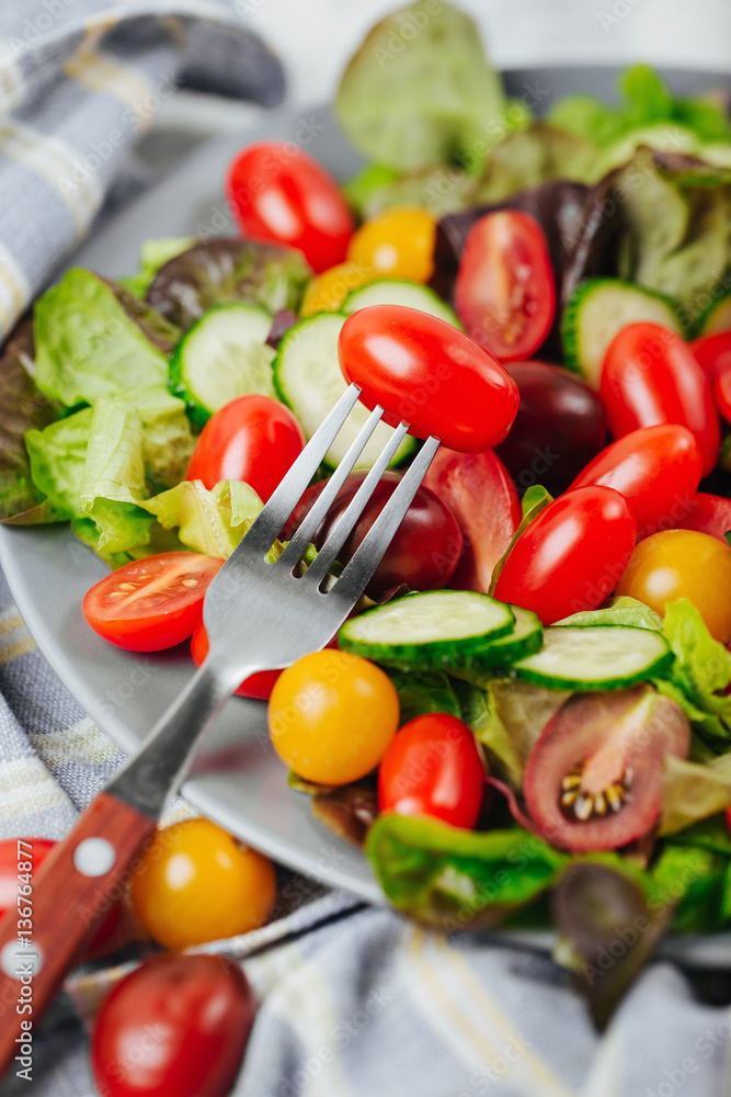 Tomato on a fork close up. Healthy salad of red and yellow cherry tomato and herbs. Tomato on a fork close up. Healthy salad of red and yellow cherry tomato and herbs.