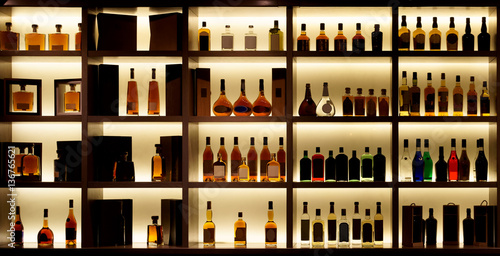 Print op canvas Various alcohol bottles in a bar, back light, logos removed