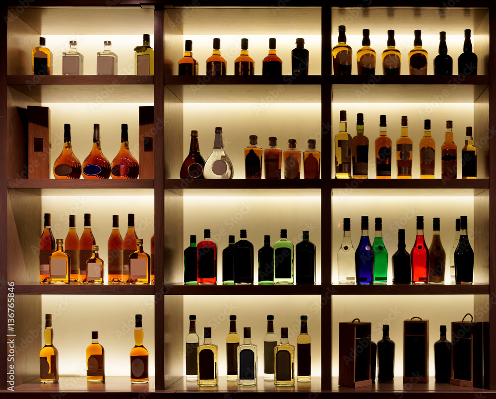 Various alcohol bottles in a bar, back light, logos removed - obrazy, fototapety, plakaty 