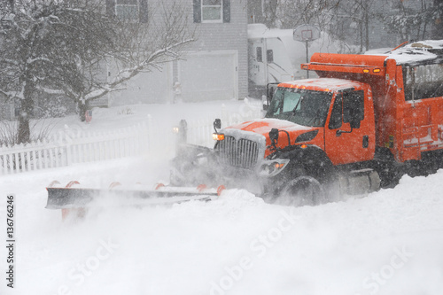snowplow truck removing snow on the street after blizzard