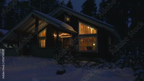 Moving by cozy wooden house in snowy forest village at winter night .