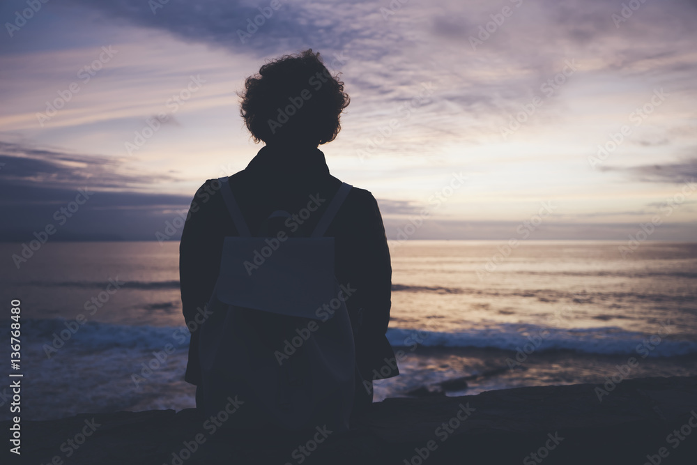 Young hipster relax beach on background ocean sunrise, silhouette romantic person looking view evening seascape, girl enjoy sunset on coast, travel holidays vacation, back figure on backdrop sea