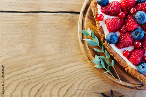 Foto A piece of berry tart with raspberries and blueberries on wooden background with