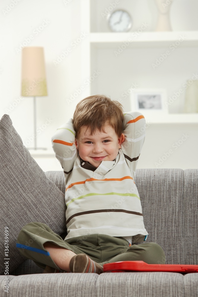 Portrait of smiling kid sitting on sofa at home Portrait of smiling kid sitting on sofa at home