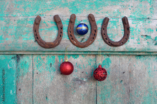 Old rusty horseshoe and Christmas baubles on wooden door
