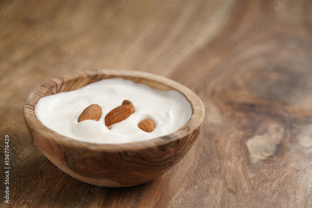 homemade yogurt with almonds in wood bowl on wooden table, shallow focus homemade yogurt with almonds in wood bowl on wooden table, shallow focus
