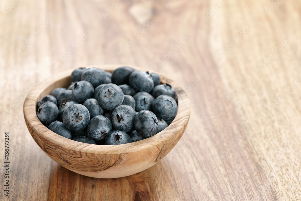 fresh blueberries in wood bowl on table with copy space, shallow focus fresh blueberries in wood bowl on table with copy space, shallow focus