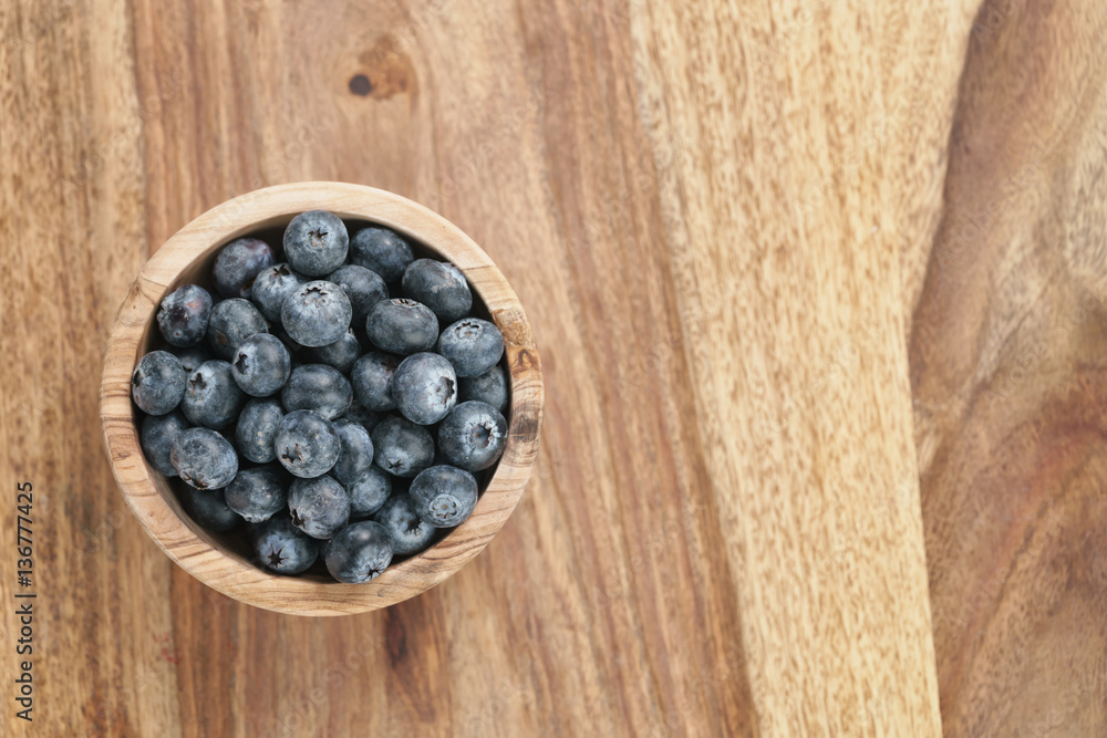 fresh blueberries in wood bowl on table with copy space, shallow focus