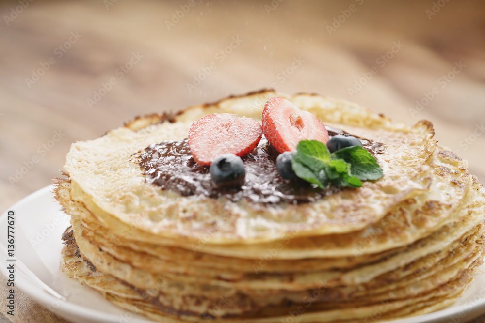 fresh blinis or crepes with melted dark chocolate, berries and sugar powder, shallow focus fresh blinis or crepes with melted dark chocolate, berries and sugar powder, shallow focus
