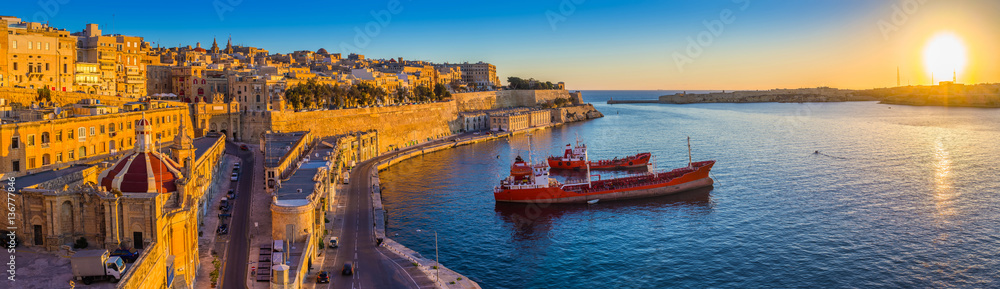 Valletta, Malta - Panoramic skyline view of Valletta and the Grand Harbor with beautiful sunrise, ships and clear blue sky Valletta, Malta - Panoramic skyline view of Valletta and the Grand Harbor with beautiful sunrise, ships and clear blue sky