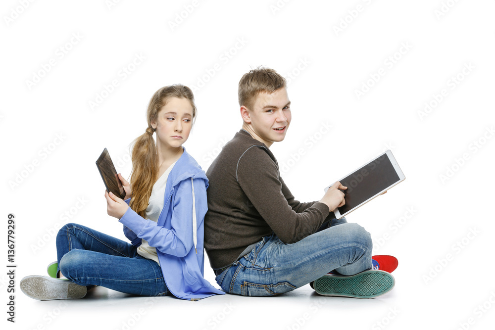 Teen boy and girl sitting with tablets Teen boy and girl sitting with tablets