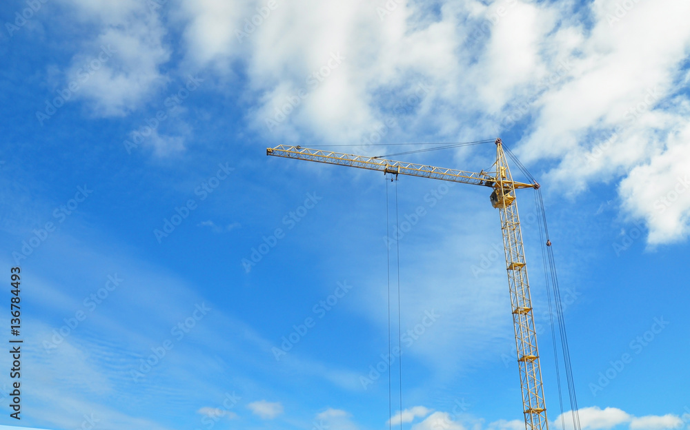 Industrial construction crane.  Big construction crane and the building. Yellow hoisting crane against cloudscape. 